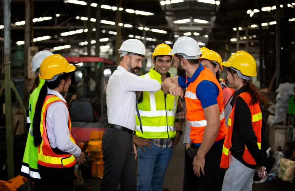 Plant team in hard hats and high-visibility vests gathered on the factory floor